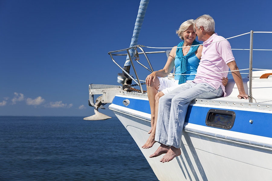 Photograph of a retired couple sitting on the bow of a yacht
